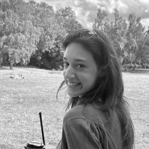 Natassa Karava smiling over the shoulder, in a park.