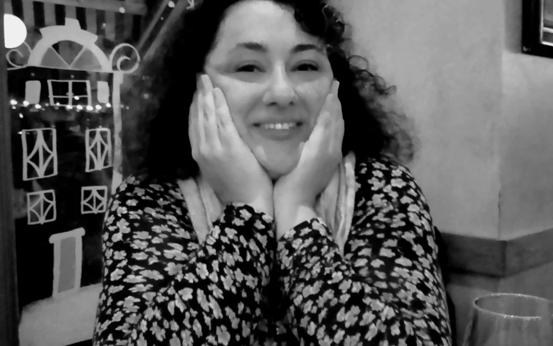 Natassa Karkatzinou smiling, chin resting in both hands.
