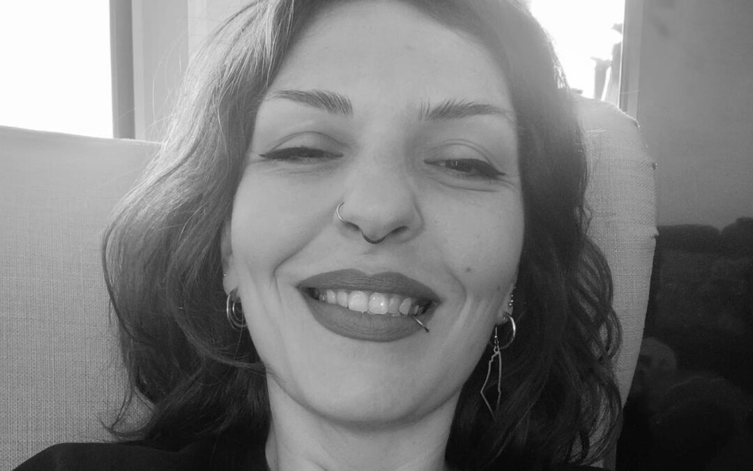 Angela Rizou smiling, with wavy hair.
