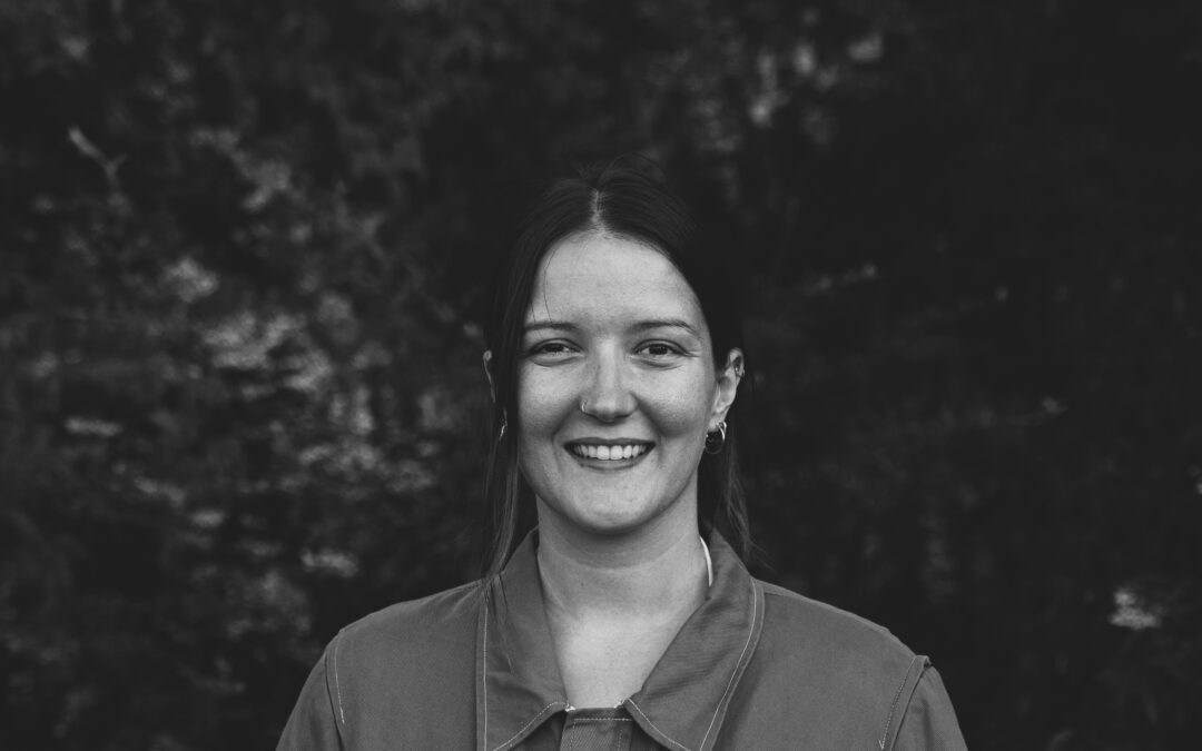 Natalie Giannopoulos smiling, in front of trees.