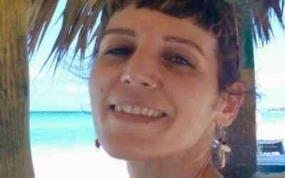 Στέλλα Καλαμπαλίκη χαμογελά, σε καλύβα στην παραλία.